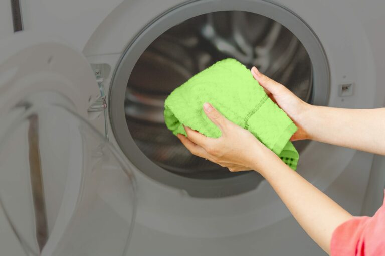 Grünes Handtuch kommt in die Waschmaschine